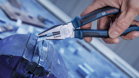 Person uses pliers to grip a metal rod held in a vise.