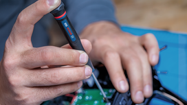 Person using a screwdriver to assemble electronic components.