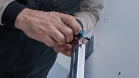 Person fastens a bracket to a wall using a screwdriver.