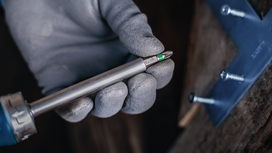 Person wearing safety equipment holds a screwdriver bit near fastened metal brackets.
