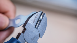 Person using wire cutters to trim a metal wire.