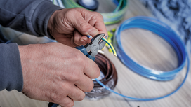 Person strips insulation from electrical wire using diagonal pliers.
