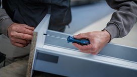Person assembles a metal frame using a hand screwdriver.