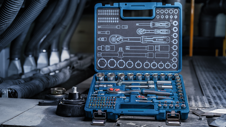 Socket and screwdriver set arranged in an open case on a factory workbench.