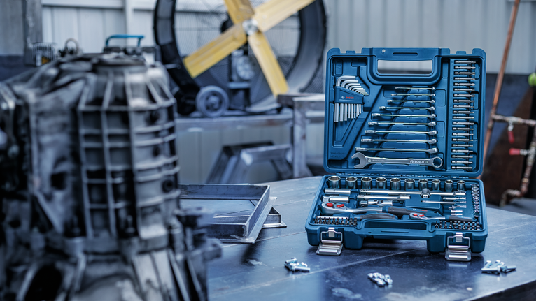 Socket and wrench set arranged in a blue case on a workshop table.
