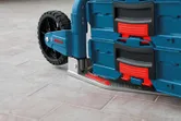 Collapsible hand truck with stacked toolboxes resting on a tiled floor.