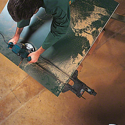 Worker operates a power saw to cut a sheet of wood.