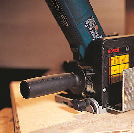 Electric planer smooths a wooden board on a workbench.