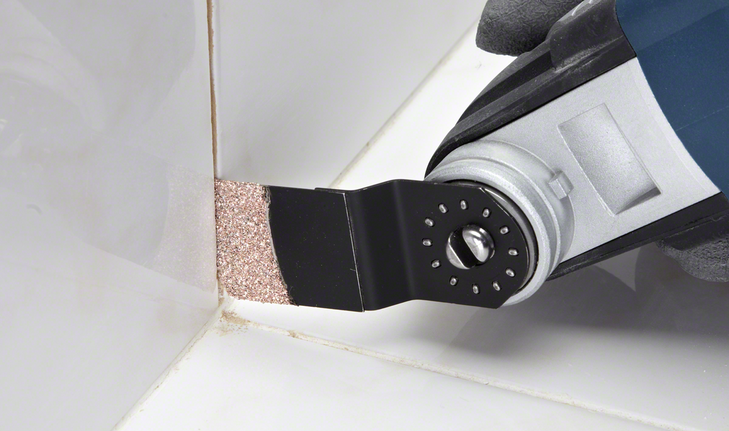 Oscillating tool with a carbide blade removes grout from bathroom tile joints.