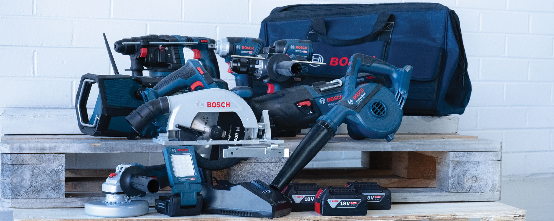 A collection of Bosch Professional tools, including a circular saw, blower, and batteries, arranged on wooden pallets.