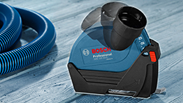 A blue Bosch Professional tool sits on a wooden surface beside a blue hose.