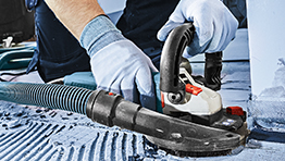 A Bosch Professional tool is used to grind a surface, with blue gloves on a worker's hands.