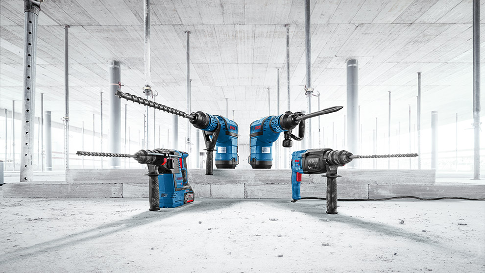 Four Bosch Professional drills arranged on a concrete floor in a construction site.