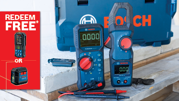 A Bosch Professional table saw is set up on a black folding stand. A person in gray attire operates it, cutting a wooden plank. A blue dust extraction hose is attached, while a red promotional banner reads "GET IT FREE*". The background features a wooden wall, creating a workshop atmosphere.